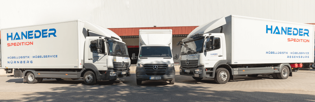 Haneder LKWs stehen vor der Lagerhalle bei Sonnenschein