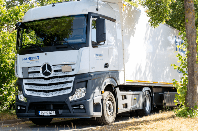LKW Haneder steht unter Bäumen