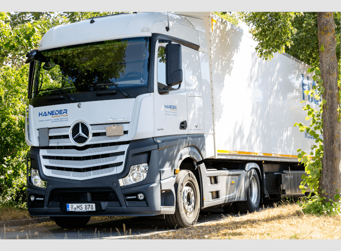 LKW Haneder steht unter Bäumen