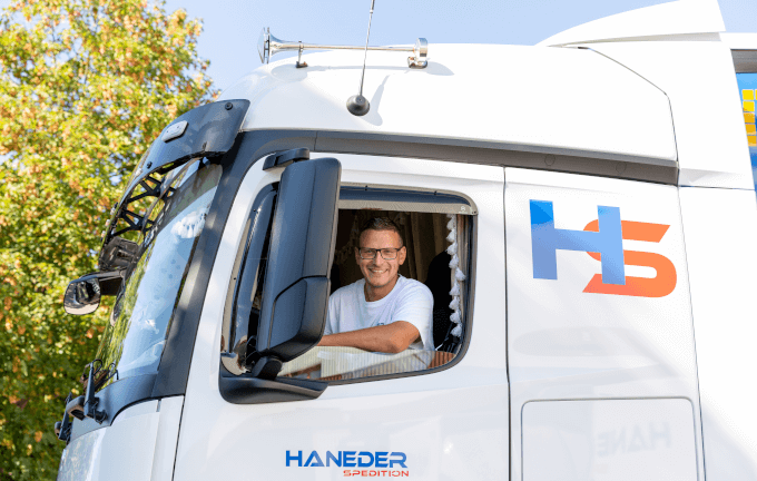 Ein LKW-Fahrer, der gerade aus der Fahrerkabine herausschaut und lächelt.